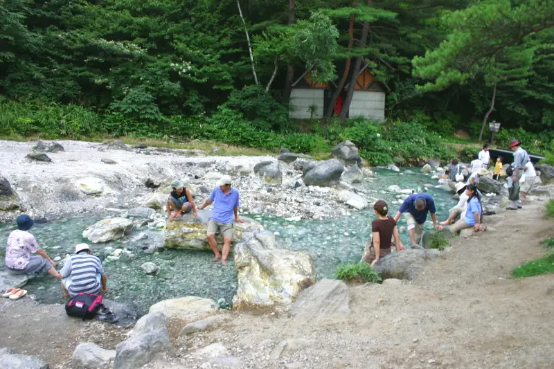 温泉の流れる川に足をつける自然の足湯