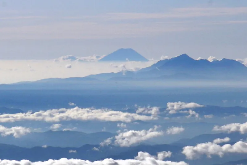 山頂をのぞかせる富士山。手前右は甲斐駒ヶ岳