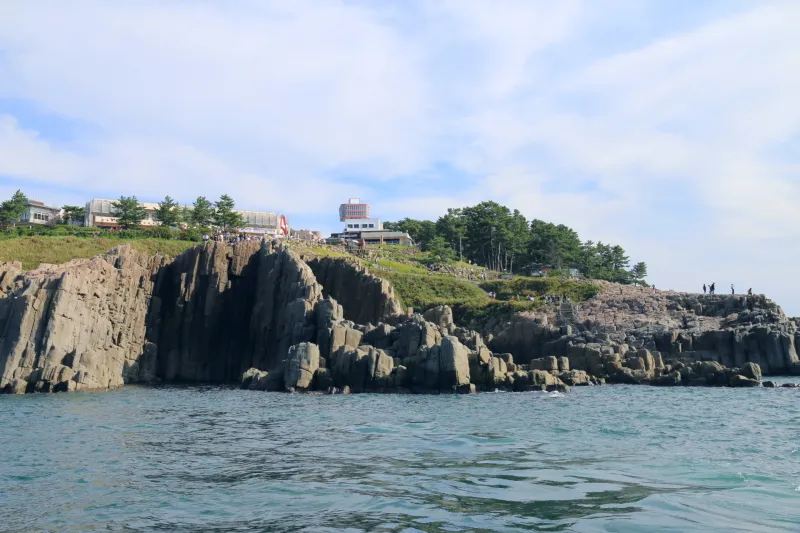 たくさんの観光客が岩の上に見える東尋坊の断崖絶壁