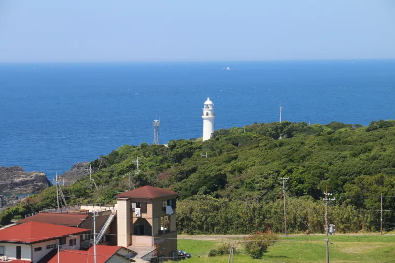 緑の森から真っ白な建物が伸びる潮岬灯台