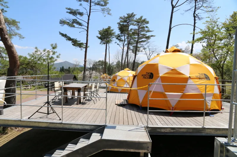 大型テントとウッドデッキのあるドームテントグランピングスタイル
