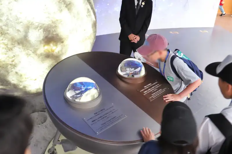 無人探査機が月から地球に持ち帰った、月の表と裏側の砂を展示